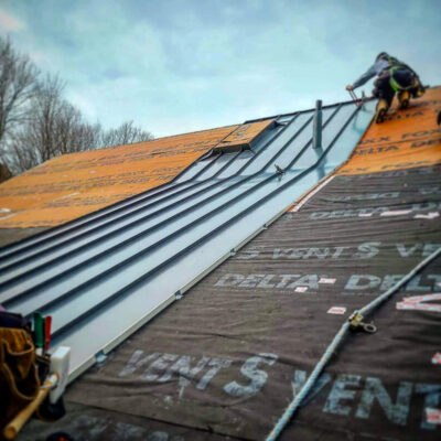 Alpro Metal Roofing working on a standing seam metal roof.