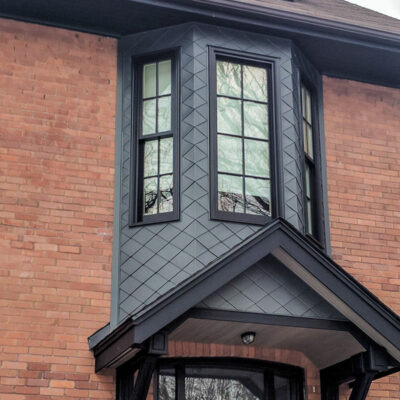 Diamond shaped metal siding on a brick him, one of Alpro Metal Roofing projects.